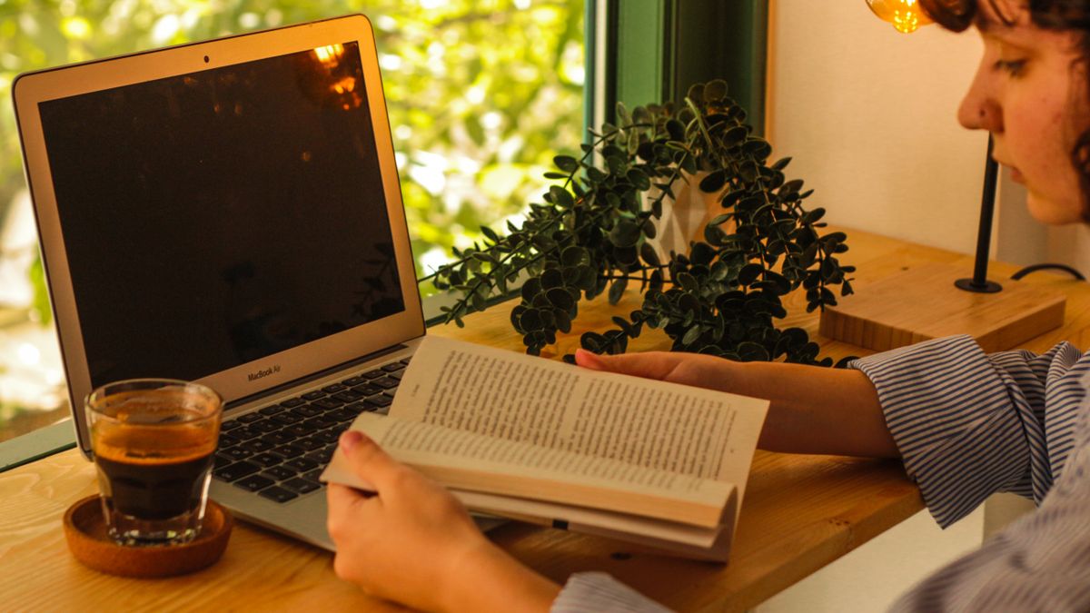 Pembaca meneliti informasi permainan dari laptop dengan buku catatan di sampingnya