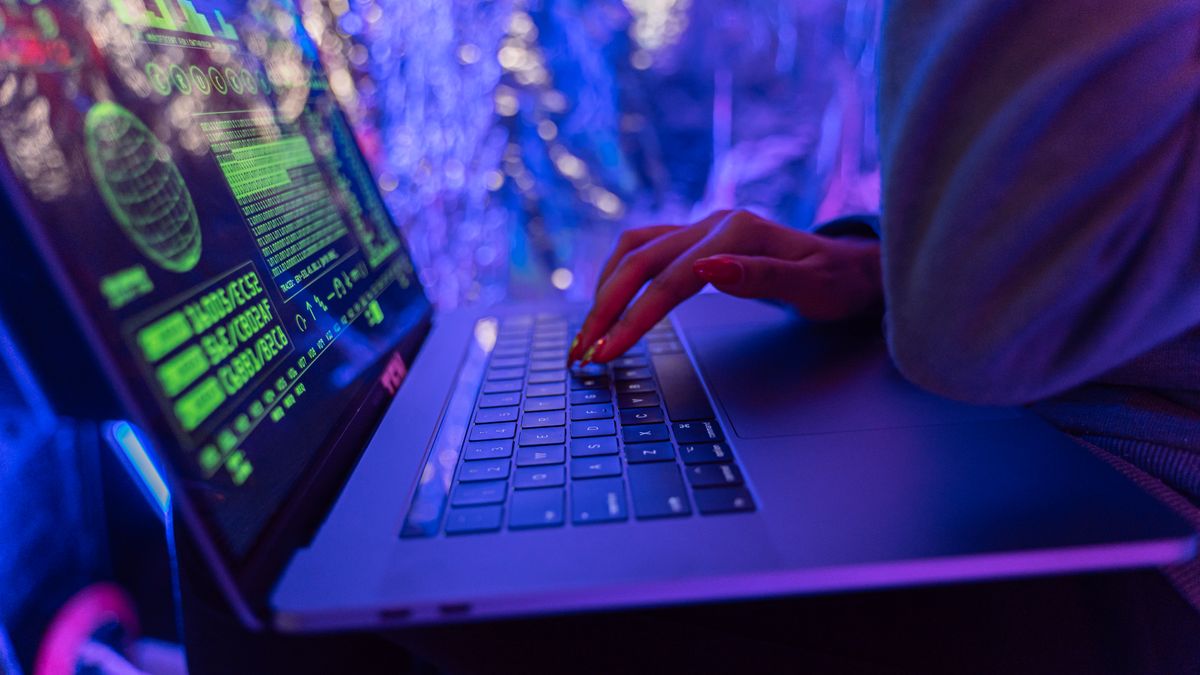 Tangan mengetik di laptop dengan tampilan keamanan siber